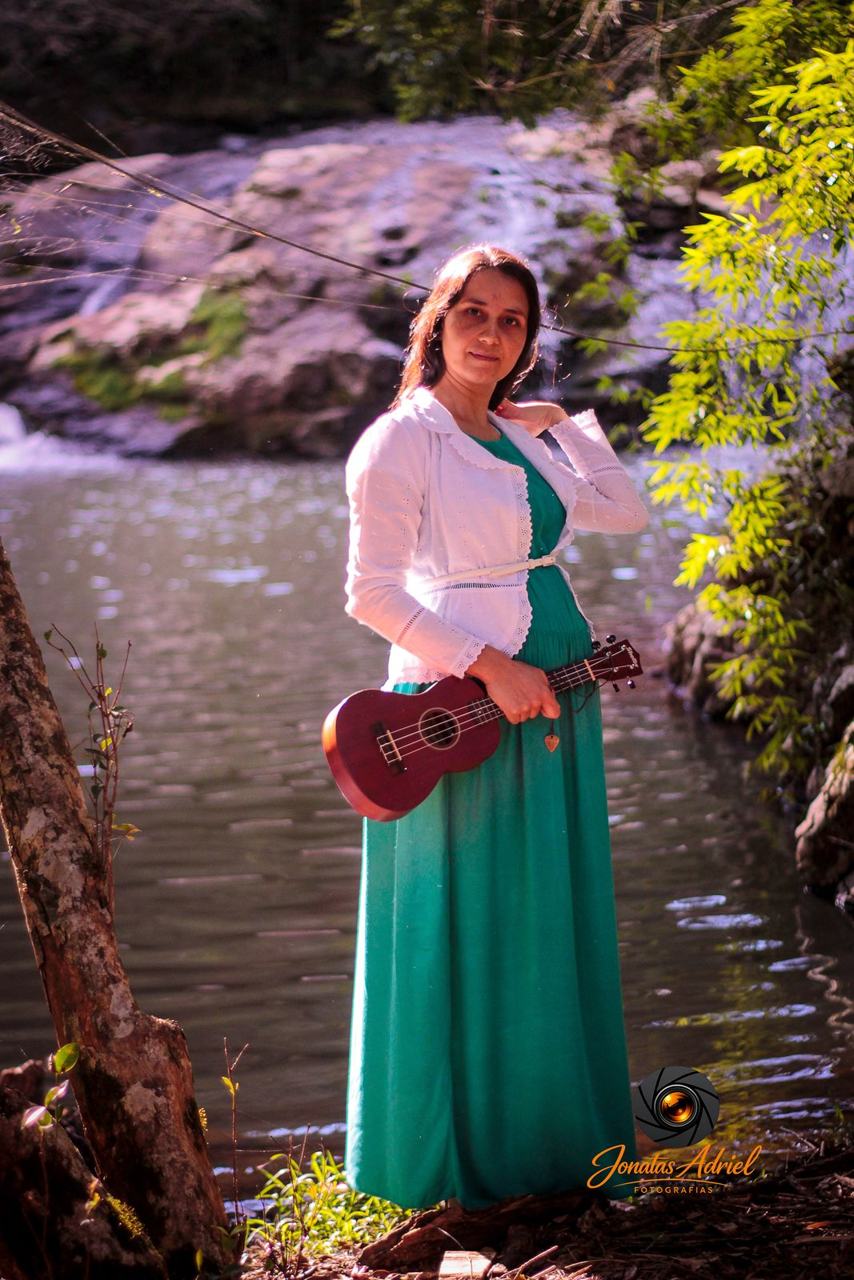 Ensaio gestante feminino à beira de um rio com ukulele
