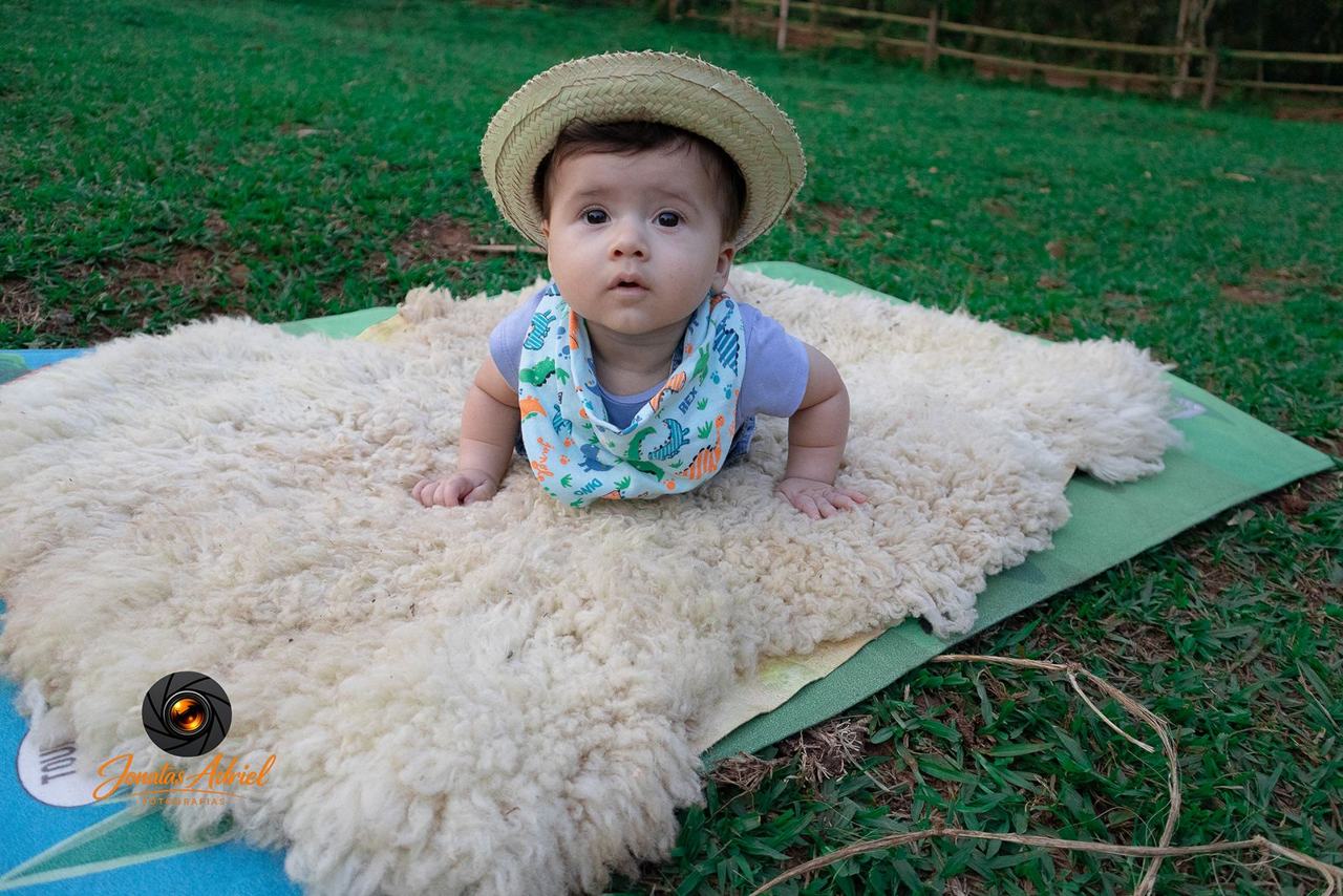 Bebê com chapéu de palha sobre tapete de lã