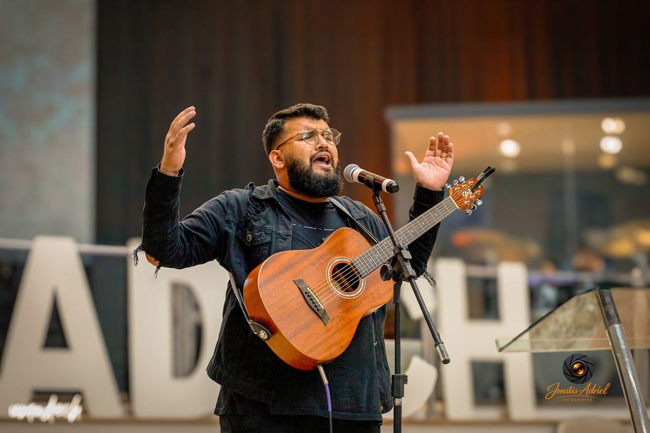 Músico cantando e tocando violão no palco em evento